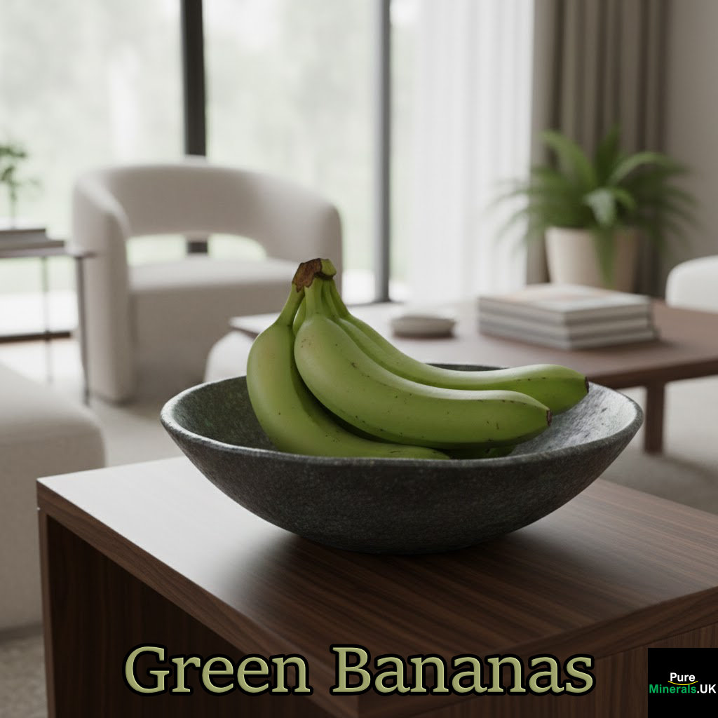 Green bananas in a bowl on a table in a lounge setting.
