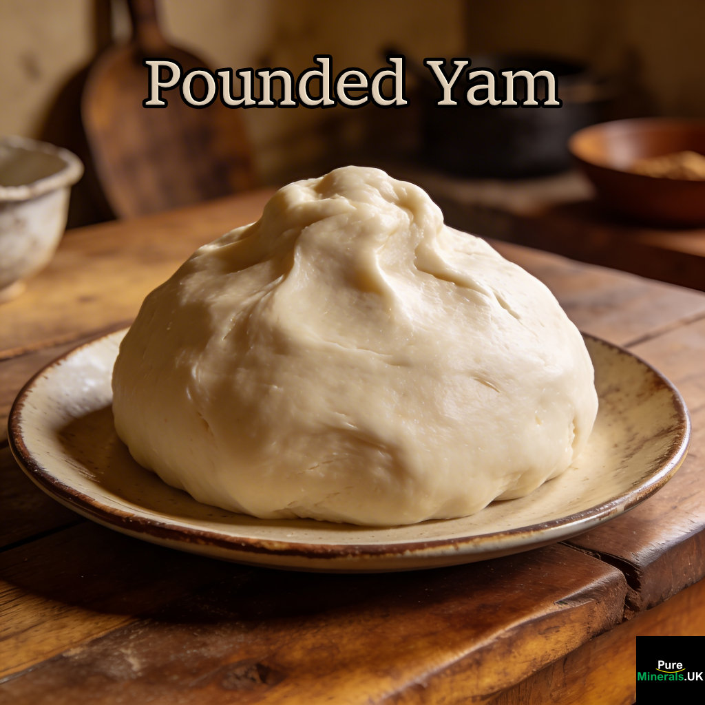 Pounded yam as a smooth, elastic mound of pale white dough with a slightly glossy surface, served on a plate in a warmly lit Nigerian kitchen with a rustic background.