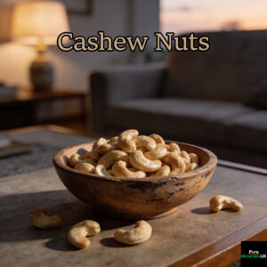 A bowl filled with golden cashew nuts sits on a wooden lounge table, with a few nuts scattered nearby.